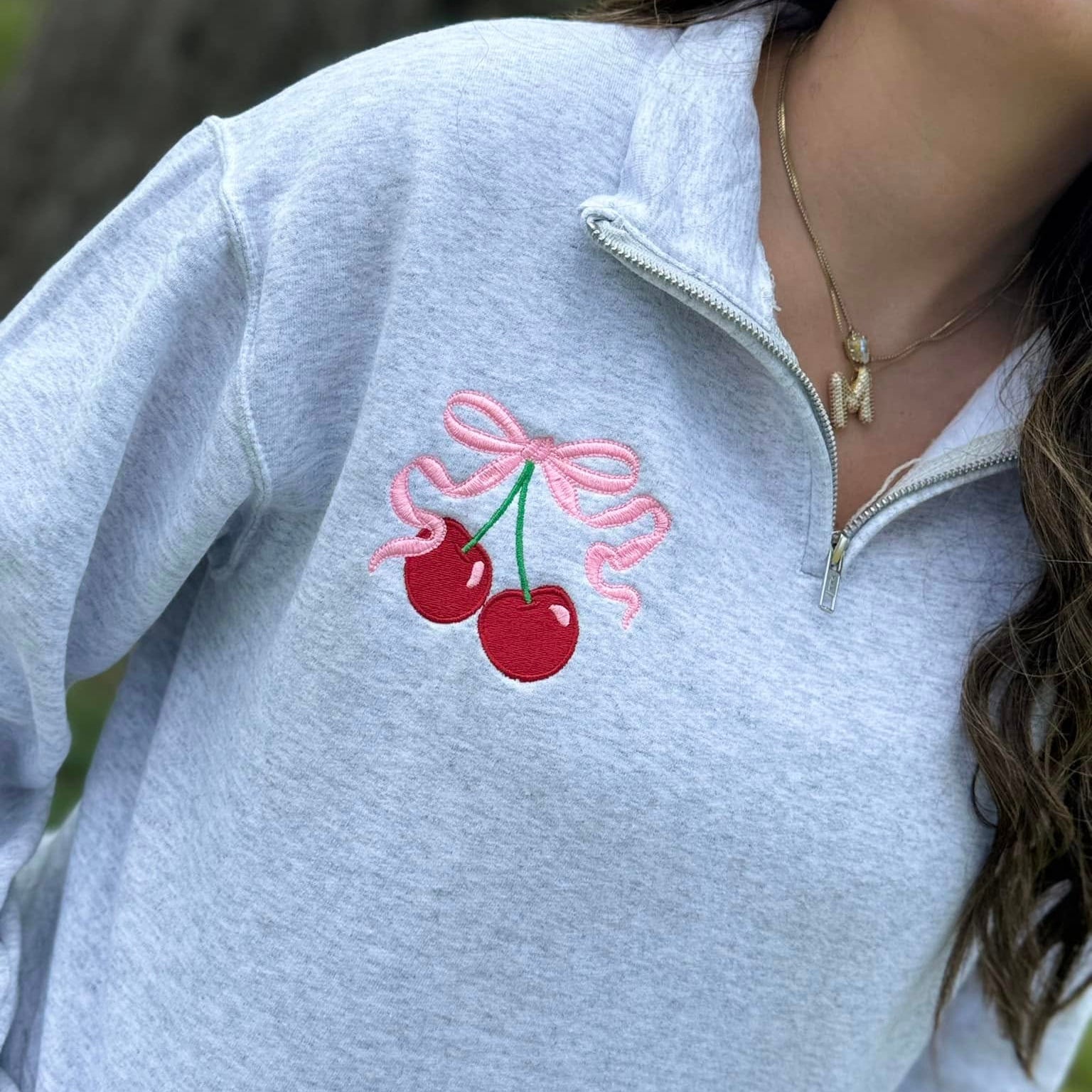 Gray sweatshirt with cherry design on a blurred natural background