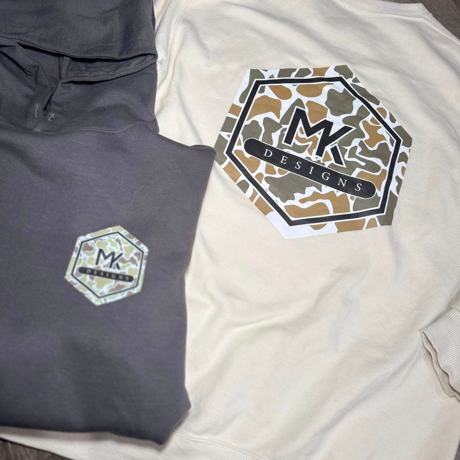 Two shirts with MK Designs logos on a neutral background