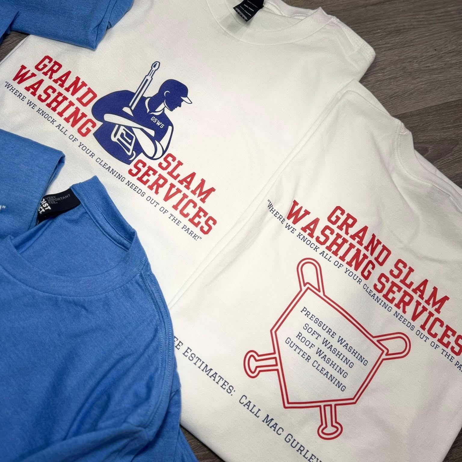 T-shirts with 'Grand Slam Services' graphics on a wooden surface