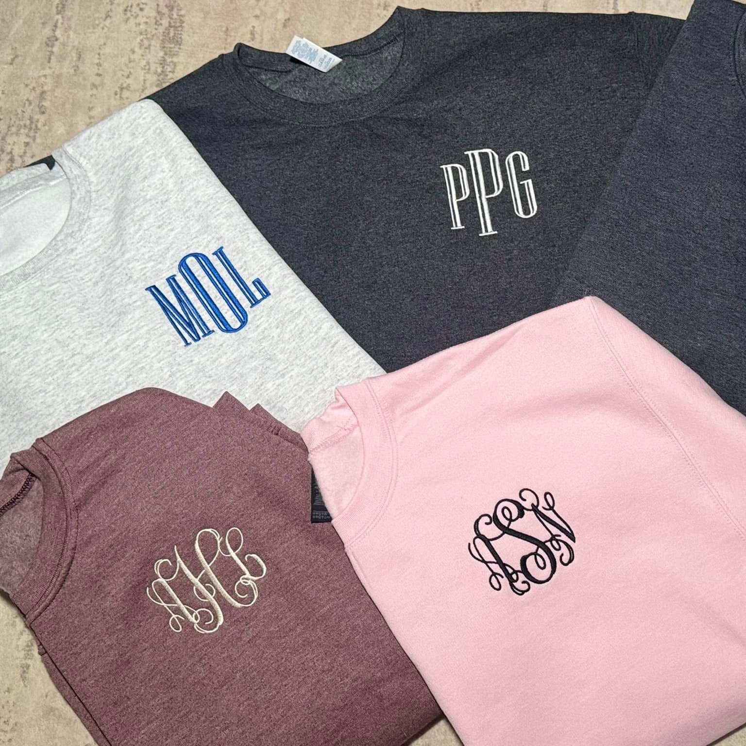 Four shirts with monogrammed initials on a wooden surface